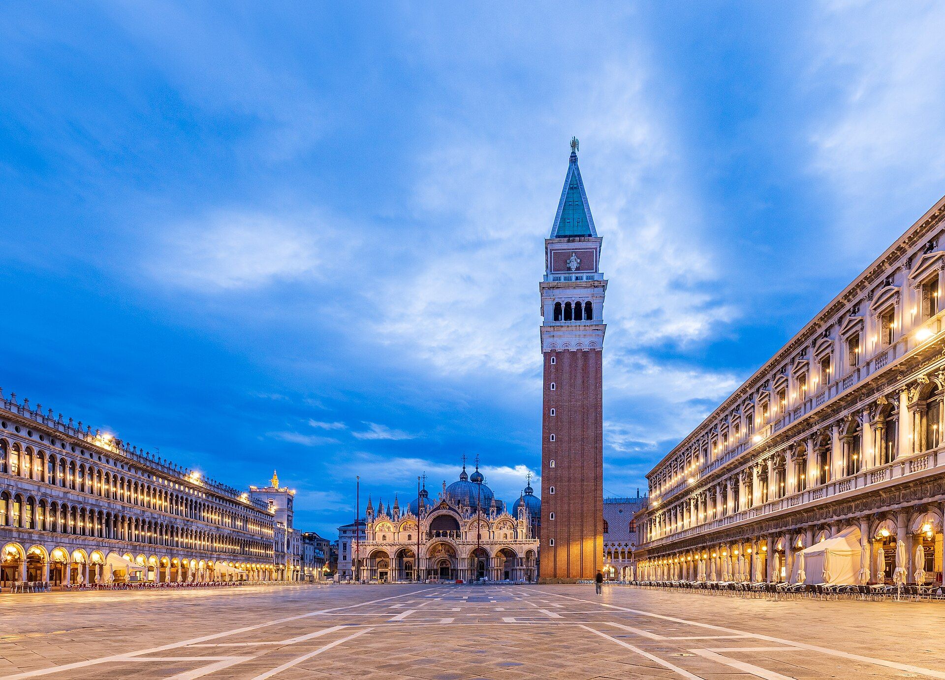 St Mark's Square at dusk with the bell tower, the basilica and lit arcades.